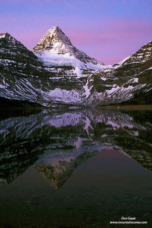 Image of Mount Assiniboine and pink skies reflected in Lake Magog